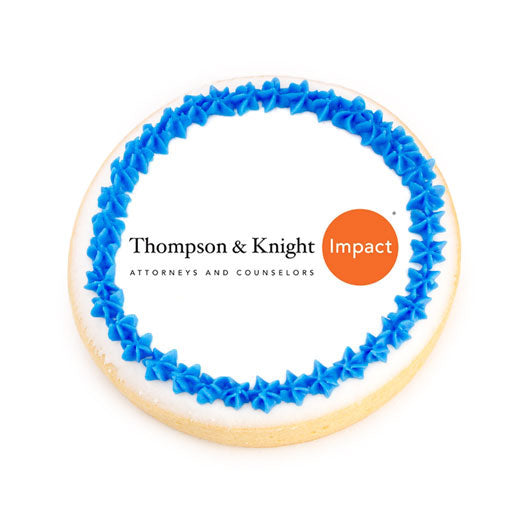 Round sugar cookie with white icing, blue frosting border, and a custom printed logo center.